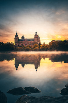Das schloss Johannisburg in Aschaffenburg Deutschland im Nebel und Sonnenaufgang mit Spiegelung