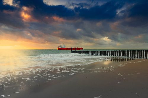 Hollandse wolkenlucht en typische golfbreker van houten palen langs de Zeeuwse kust