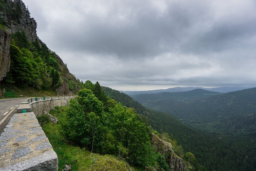 Frankreich - Rechts abbiegende Straße auf dem Gipfel eines Berges mit bewaldetem Tal von adventure-photos