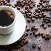 Weiße Tasse mit starkem schwarzem Kaffee auf einem rustikalen Holztisch mit einigen Bohnen, Kopierra von Maren Winter