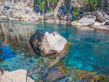 Einsamer Felsen im leuchtend türkisfarbenen fließenden Fluss von Nature Life Ambience
