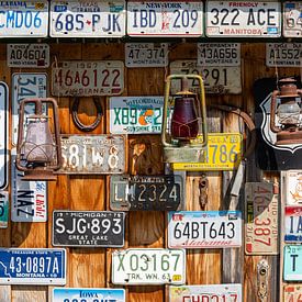 Alte Autokennzeichen und Öllampen an einer Holzwand in Kanada von Inge van den Brande