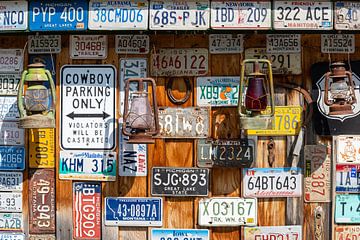 Alte Autokennzeichen und Öllampen an einer Holzwand in Kanada