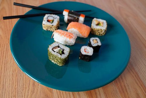 Sushi op een groen bord met eetstokjes