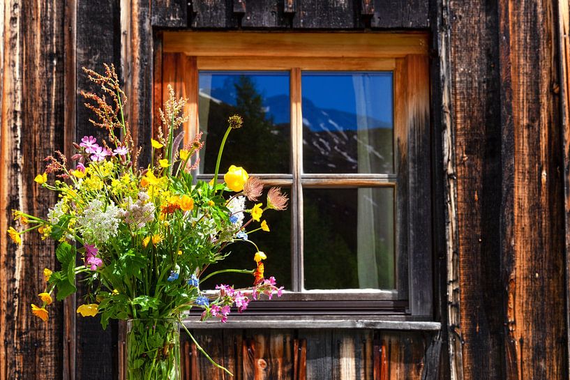 Wildblumenstrauß vor einem Fenster einer Almhütte von Studio17