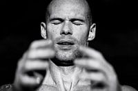 Sport atleet man met emotie en gesloten ogen en concentratie tilt handen omhoog. Kracht en focus.