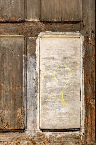 Wooden light brown door with yellow white and blue heart on white surface