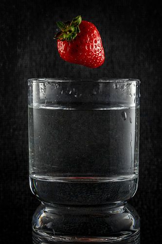 Het moment net voordat een aardbei in het water valt