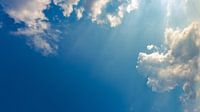 Blauwe lucht met wolken en zonnestralen