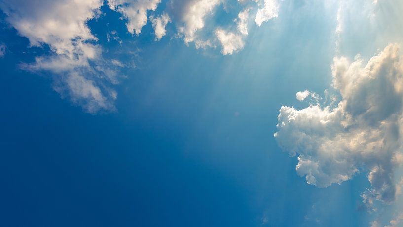 Blauer Himmel mit Wolken und Sonnenstrahlen von Robert Ruidl