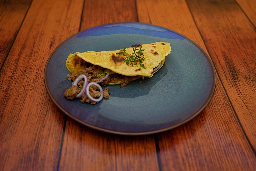 Taco with minced meat-avocado-onion filling arranged on a plate. by Babetts Bildergalerie