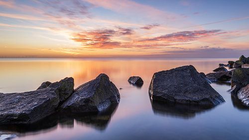 Lange sluitertijd bij zonsopkomst aan het IJsselmeer met rotsen bij Den Oever