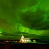 Noorderlicht boven kerkje in IJsland van Chris Stenger