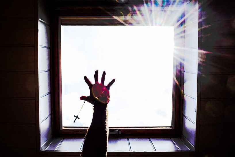 Hand mit Kreuz, die nach Licht greift von DiJa Photography