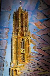 Na een regenbui weerspiegelt de Utrechtse Domtoren in een plas. sur Margreet van Beusichem