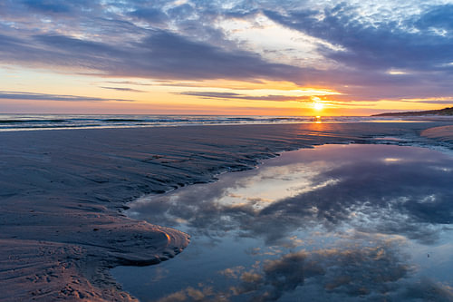 Romantische zonsondergang boven een zandstrand aan de Oostzee met dramatische wolken – vakantie- en reisconcept