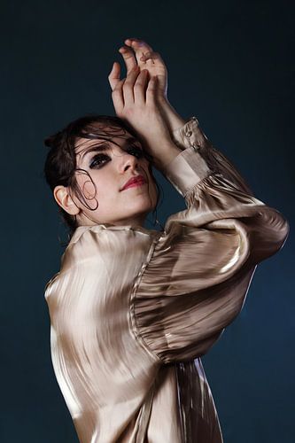 Portret van vrouw met gouden blouse op blauwe achtergrond
