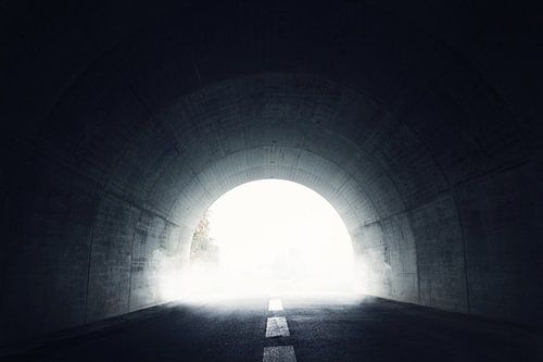 Tunnel sombre avec lumière et brouillard au bout du tunnel