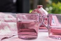 Set van roze theeglazen met vloeistof voor een met name roze achtergrond met een vaasje