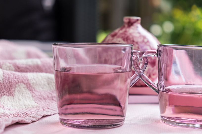 Satz rosa Teegläser mit Flüssigkeit für einen besonders rosa Hintergrund mit einer Vase von Idema Media