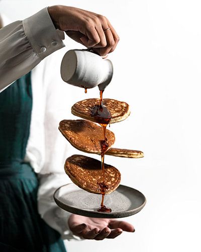 Schwimmende Pfannkuchen mit fließendem Sirup