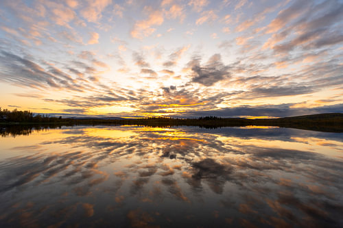 Wolkenspiegel bij zonsondergang boven een meer