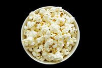 Kommetje gevuld met popcorn op een zwarte achtergrond