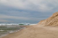 Golven met schuimkoppen, goudgeel stuivend strandzand, aan de kust van de Atlantische Oceaan bij Obidos, Portugal.