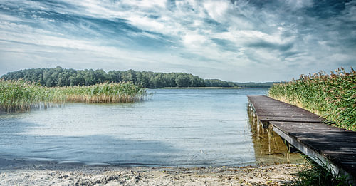 Prachtig, afgelegen strand en steiger in Polen in hartje zomer. Eenzame idylle zonder mensen in de vrije natuur. Houten steiger op het strand en aanlegsteiger voor boten. Fantastische natuur in een afgelegen paradijs.