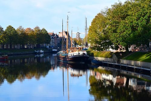 Ansicht des Kanals in Dokkum, Friesland (Grootdiep), mit Booten und Bäumen, die sich im Wasser spiegeln.