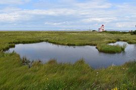 A small lighthouse on the riverbank by Claude Laprise