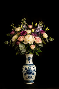 Delftblaue Vase mit Blumen auf schwarzem Hintergrund