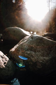 Zonnestralen ontmoeten stenen in het water van Katrin Friedl Fotografie