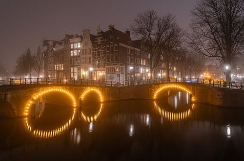 De Amsterdamse Grachtengordel in de mist in de avond