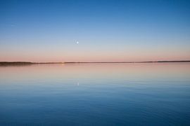 The turquoise lake at dawn. smooth blue and turquoise lake surface at dawn, red and orange and sky b by Michael Semenov