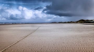 Verlaten strand  met donkerblauw lucht en aanstormende regenbui van Marianne van der Zee