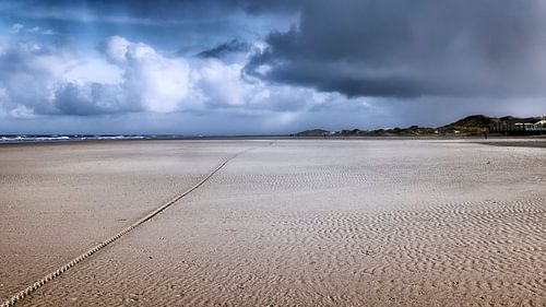 Verlaten strand  met donkerblauw lucht en aanstormende regenbui