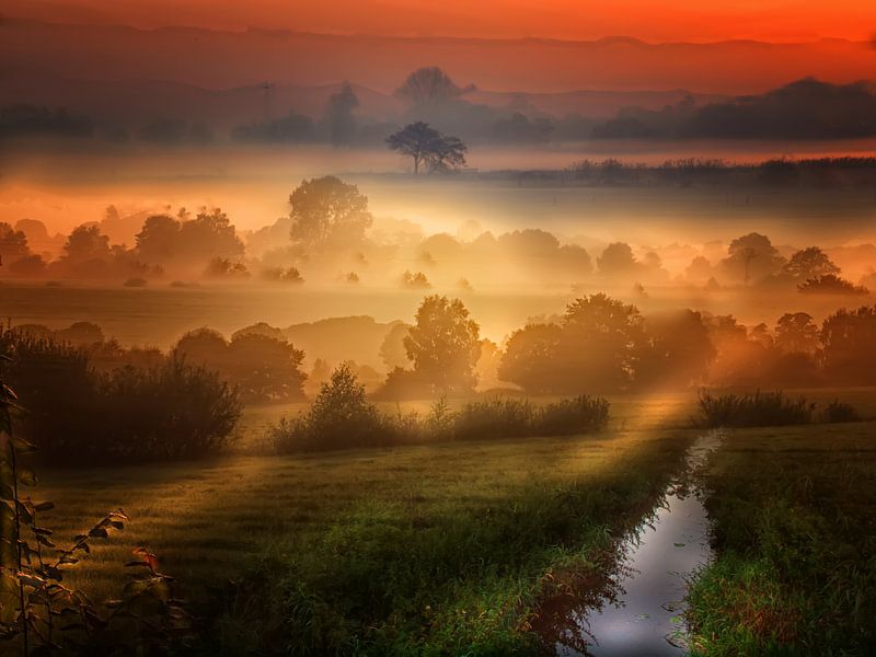 De zon komt rood op boven het landschap van Peter Roder