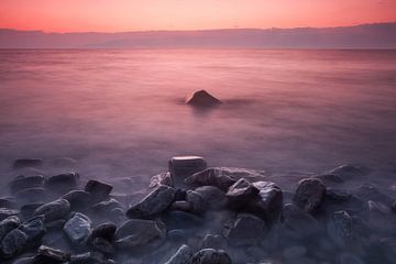 Heldere roze zonsondergang op het baikalmeer, stenen op de voorgrond, lange belichting van Michael Semenov