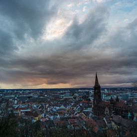 Romantische oranje zonsondergang boven de stad Freiburg in Duitsland met het oude kerkgebouw van adventure-photos