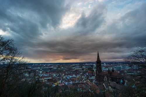 Romantische oranje zonsondergang boven de stad Freiburg in Duitsland met het oude kerkgebouw