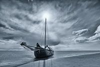 Black-and-white photo of a dry-fall sailing ship on a sandbank in the Wadden Sea