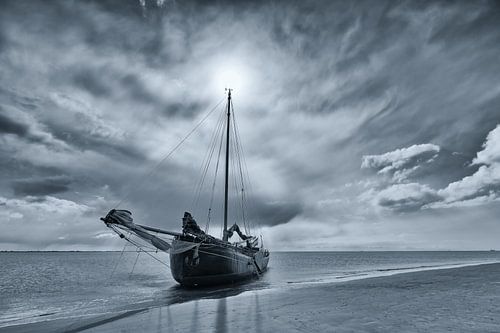 Photo en noir et blanc d'un voilier en chute libre sur un banc de sable dans la mer des Wadden