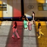Lady in green and red suitcase in coloured light at station