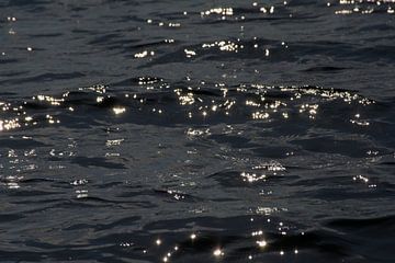 Dunkles wellenförmiges Wasser mit Reflexion der Sonne