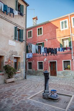 Huis aan plein met pomp op Murano, Venetie, Italie van Joost Adriaanse
