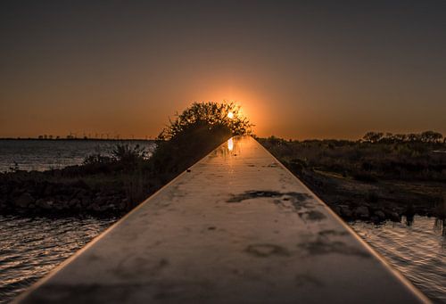 Zonsondergang langs de leuning van een brug.