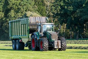 Grüner Traktor holt im Sommer in den Niederlanden geschnittenes Gras ab