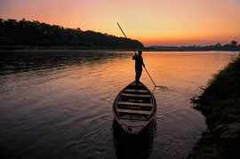 Sonnenaufgang mit einem Bootsführer auf dem Fluss im Chitwan-Nationalpark von Laimute Kuriene