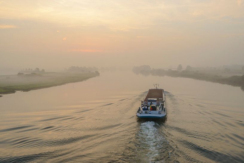 Binnenvaartschip op de rivier de IJssel tijdens zonsopkomst van Sjoerd van der Wal